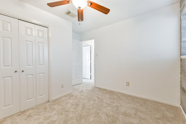 unfurnished bedroom with ceiling fan, a closet, and light colored carpet