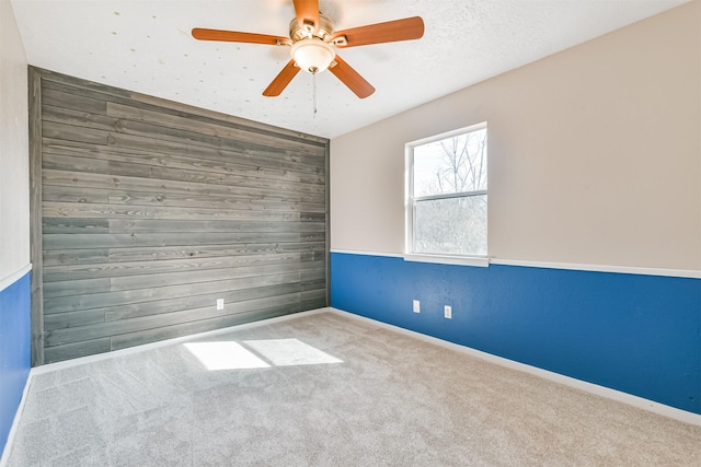 unfurnished room with ceiling fan, light colored carpet, and wooden walls