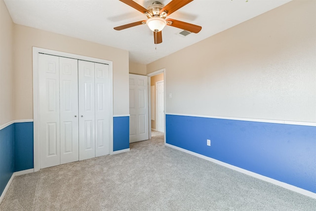 unfurnished bedroom with ceiling fan, light carpet, and a closet