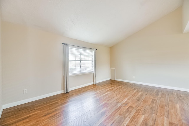 spare room with light wood-type flooring and vaulted ceiling