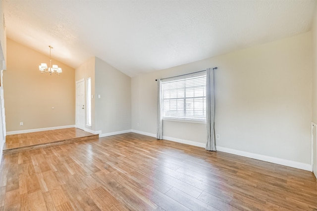 unfurnished room featuring light hardwood / wood-style floors, vaulted ceiling, and a notable chandelier