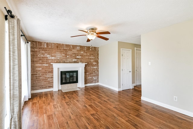 unfurnished living room featuring hardwood / wood-style floors, ceiling fan, a fireplace, and a textured ceiling