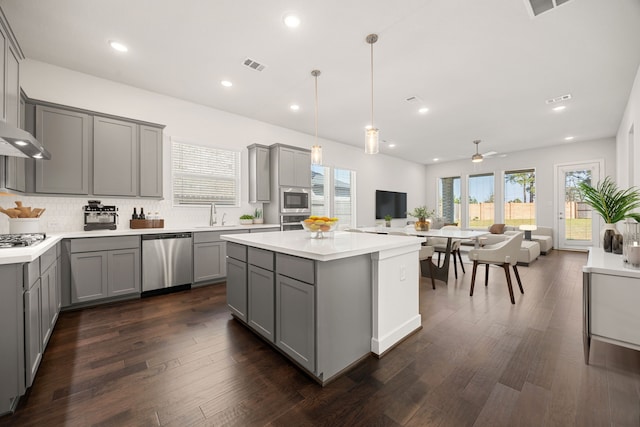 kitchen featuring gray cabinetry, ceiling fan, stainless steel appliances, and decorative light fixtures