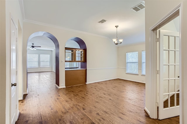 empty room with hardwood / wood-style flooring, ceiling fan with notable chandelier, and ornamental molding