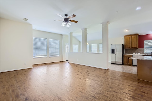 unfurnished living room featuring ornate columns, light wood-type flooring, and ceiling fan