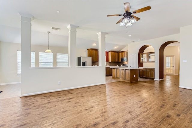 unfurnished living room with decorative columns, vaulted ceiling, hardwood / wood-style floors, and ceiling fan