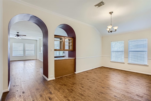 spare room featuring dark wood-type flooring, lofted ceiling, ornamental molding, and ceiling fan with notable chandelier