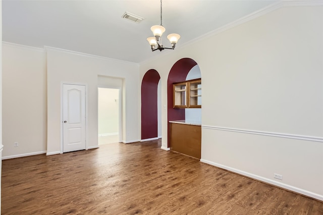 empty room with dark hardwood / wood-style flooring, ornamental molding, and an inviting chandelier