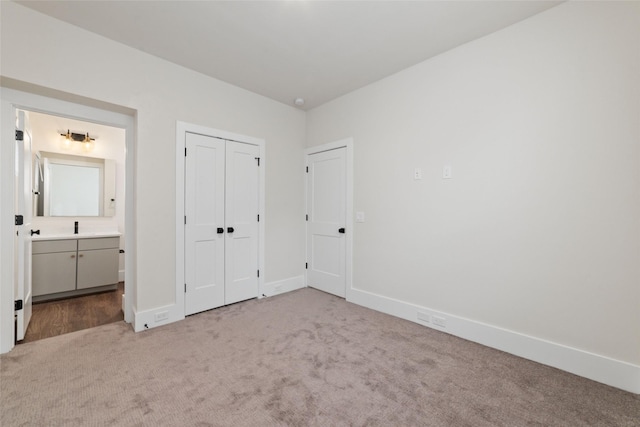 unfurnished bedroom featuring light carpet, ensuite bathroom, and a closet