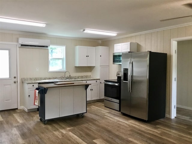 kitchen featuring an AC wall unit, crown molding, dark hardwood / wood-style floors, appliances with stainless steel finishes, and white cabinetry