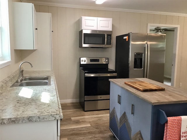 kitchen featuring crown molding, sink, light hardwood / wood-style flooring, white cabinetry, and stainless steel appliances