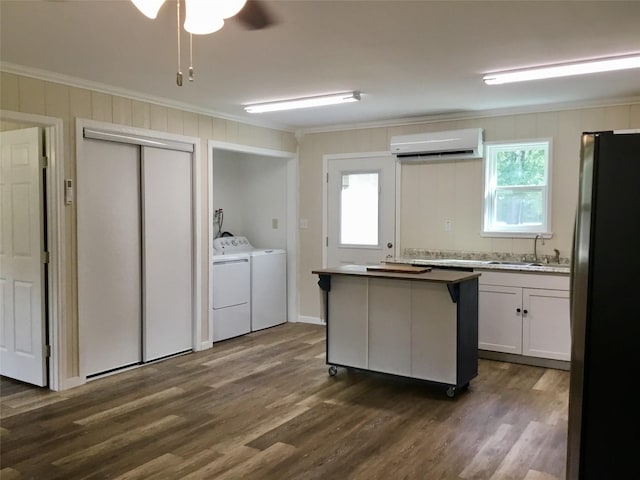 kitchen featuring crown molding, white cabinetry, washing machine and clothes dryer, a kitchen island, and fridge