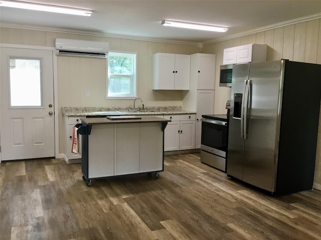 kitchen featuring sink, a wall mounted AC, appliances with stainless steel finishes, white cabinets, and ornamental molding