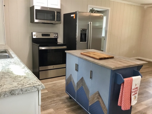 kitchen with a center island, light wood-type flooring, stainless steel appliances, and blue cabinets