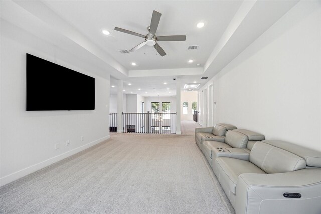 living room with ceiling fan, light colored carpet, and a tray ceiling