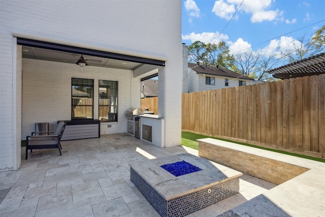 view of patio featuring grilling area, ceiling fan, exterior kitchen, and a fire pit