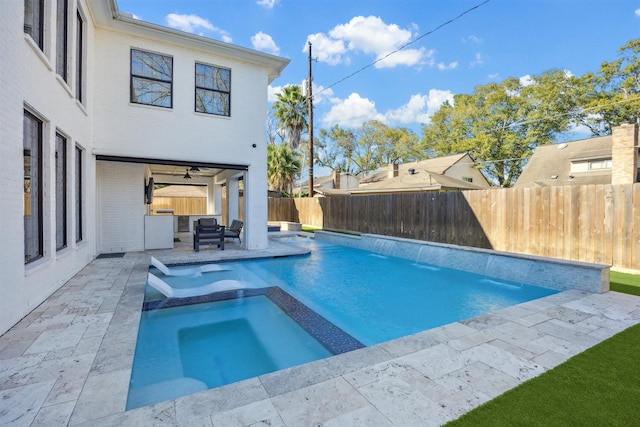 view of swimming pool with a fenced backyard, a pool with connected hot tub, a ceiling fan, and a patio