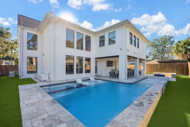 back of property featuring a patio, a lawn, a fenced backyard, and a pool with connected hot tub