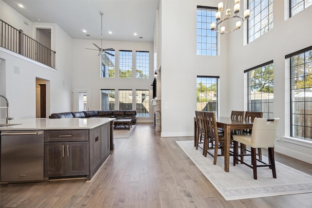 dining room with a wealth of natural light, sink, a high ceiling, and light wood-type flooring