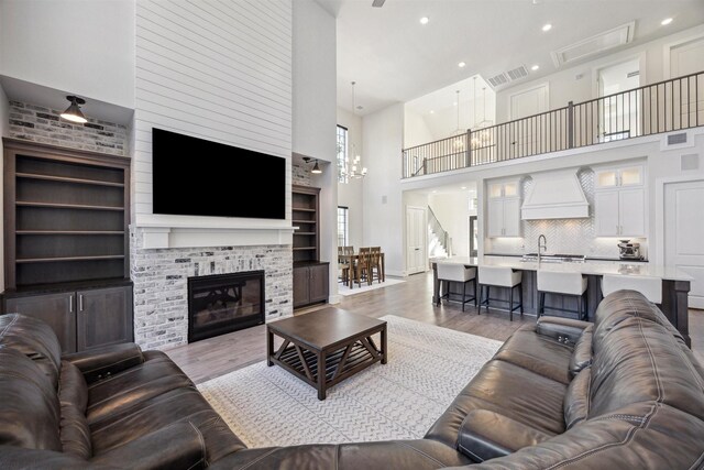 living room featuring ceiling fan with notable chandelier, sink, a high ceiling, and light hardwood / wood-style flooring