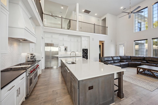 kitchen with custom exhaust hood, backsplash, a high ceiling, sink, and built in appliances