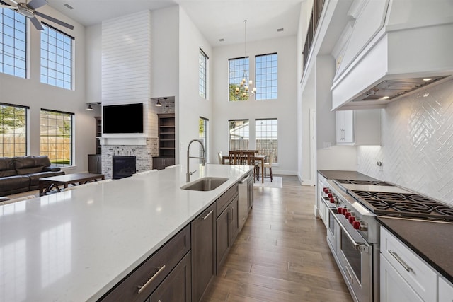 kitchen with premium range hood, a sink, open floor plan, hanging light fixtures, and appliances with stainless steel finishes