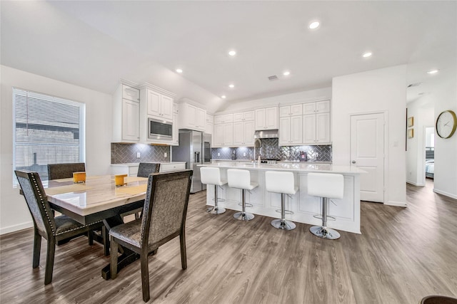 kitchen featuring a breakfast bar, stainless steel appliances, a kitchen island with sink, sink, and white cabinets