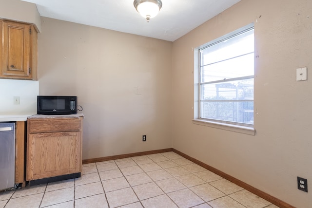 kitchen featuring stainless steel dishwasher, plenty of natural light, and light tile patterned floors