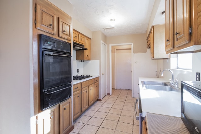 kitchen featuring sink, gas stovetop, a textured ceiling, black oven, and light tile patterned flooring