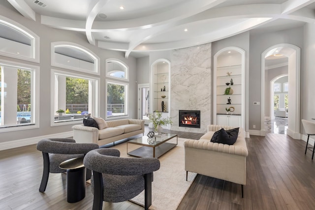 living room featuring built in shelves, a premium fireplace, and hardwood / wood-style floors