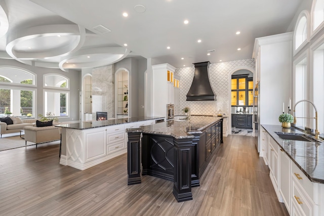 kitchen featuring white cabinetry, custom exhaust hood, a spacious island, and sink