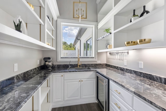 kitchen with dark hardwood / wood-style flooring, dark stone counters, beverage cooler, sink, and white cabinets