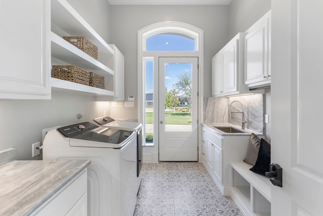 laundry room with cabinets, washing machine and dryer, and sink