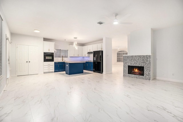 kitchen featuring a center island, black appliances, white cabinets, a fireplace, and blue cabinetry