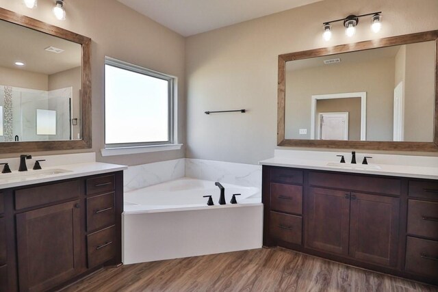 bathroom with a tub to relax in, hardwood / wood-style floors, and vanity