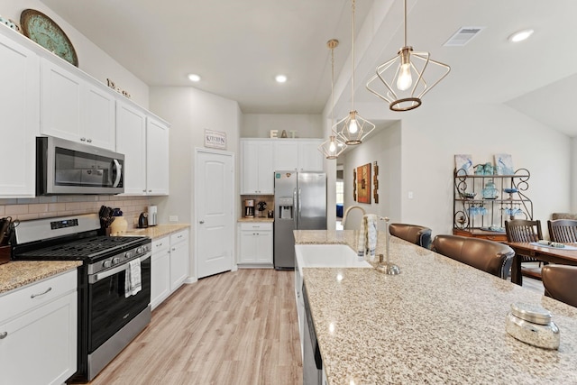 kitchen with decorative backsplash, pendant lighting, stainless steel appliances, and white cabinetry