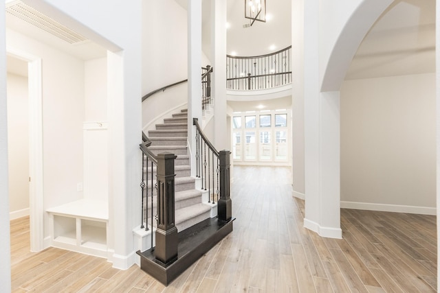 entryway with a high ceiling, light hardwood / wood-style floors, and a notable chandelier