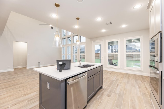 kitchen with stainless steel appliances, sink, pendant lighting, a center island with sink, and light hardwood / wood-style floors