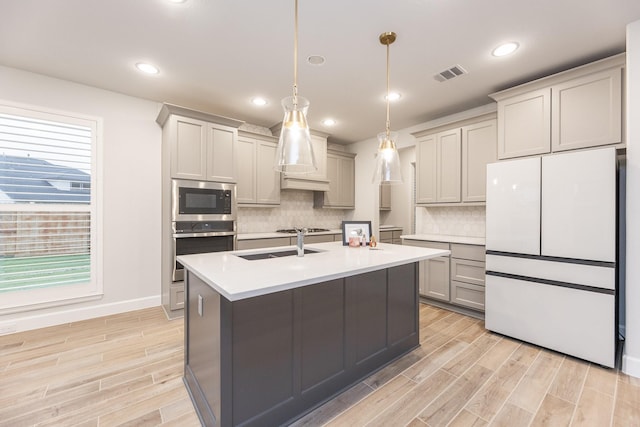 kitchen featuring hanging light fixtures, stainless steel appliances, tasteful backsplash, light hardwood / wood-style floors, and gray cabinets