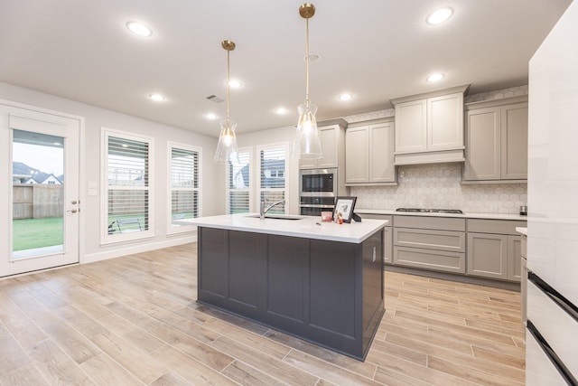 kitchen with gray cabinetry, stainless steel gas stovetop, and decorative light fixtures