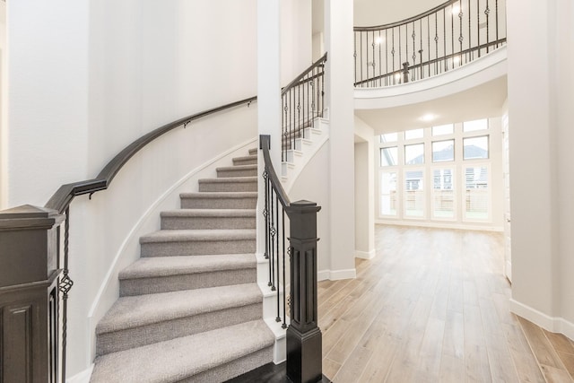 stairs featuring a towering ceiling and wood-type flooring