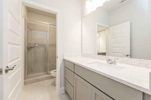 bathroom featuring tile patterned floors, vanity, a shower with shower door, and toilet