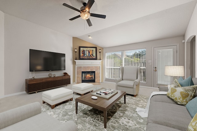 living room with light colored carpet, vaulted ceiling, ceiling fan, and a tiled fireplace