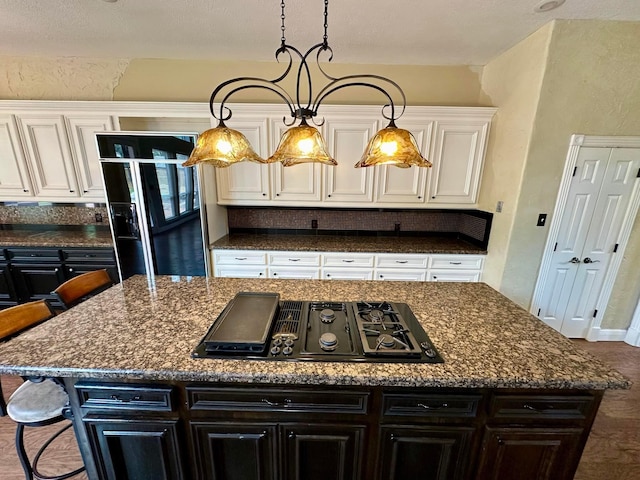 kitchen with a kitchen bar, white cabinets, a kitchen island, and black appliances