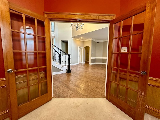 corridor with carpet floors, an inviting chandelier, and crown molding