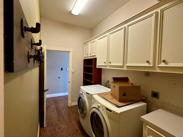 laundry room with a textured ceiling, washer and dryer, cabinets, and dark wood-type flooring