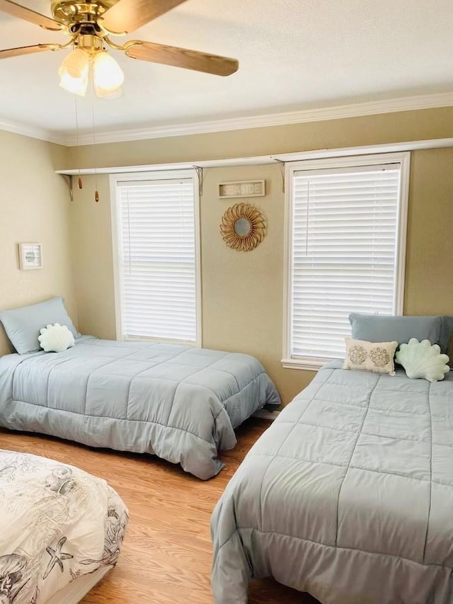 bedroom with hardwood / wood-style flooring, ceiling fan, and ornamental molding