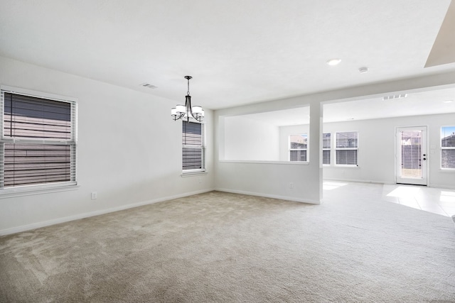 carpeted spare room featuring a notable chandelier