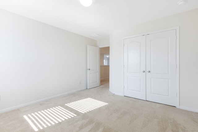 unfurnished bedroom featuring a closet and light colored carpet