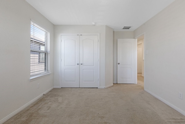 unfurnished bedroom with light carpet and a closet